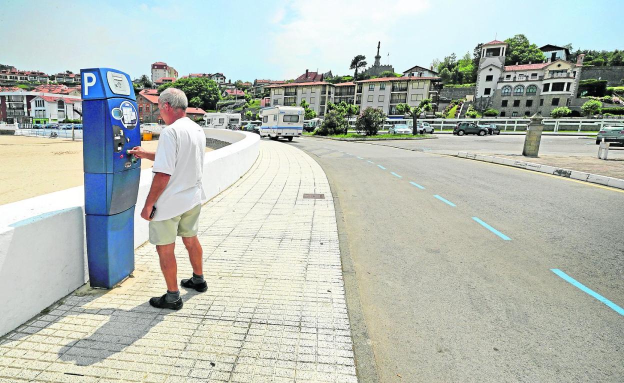 Imagen de archivo de un hombre abonando el precio por estacionar en la zona azul de aparcamiento junto a la playa de Comillas. 