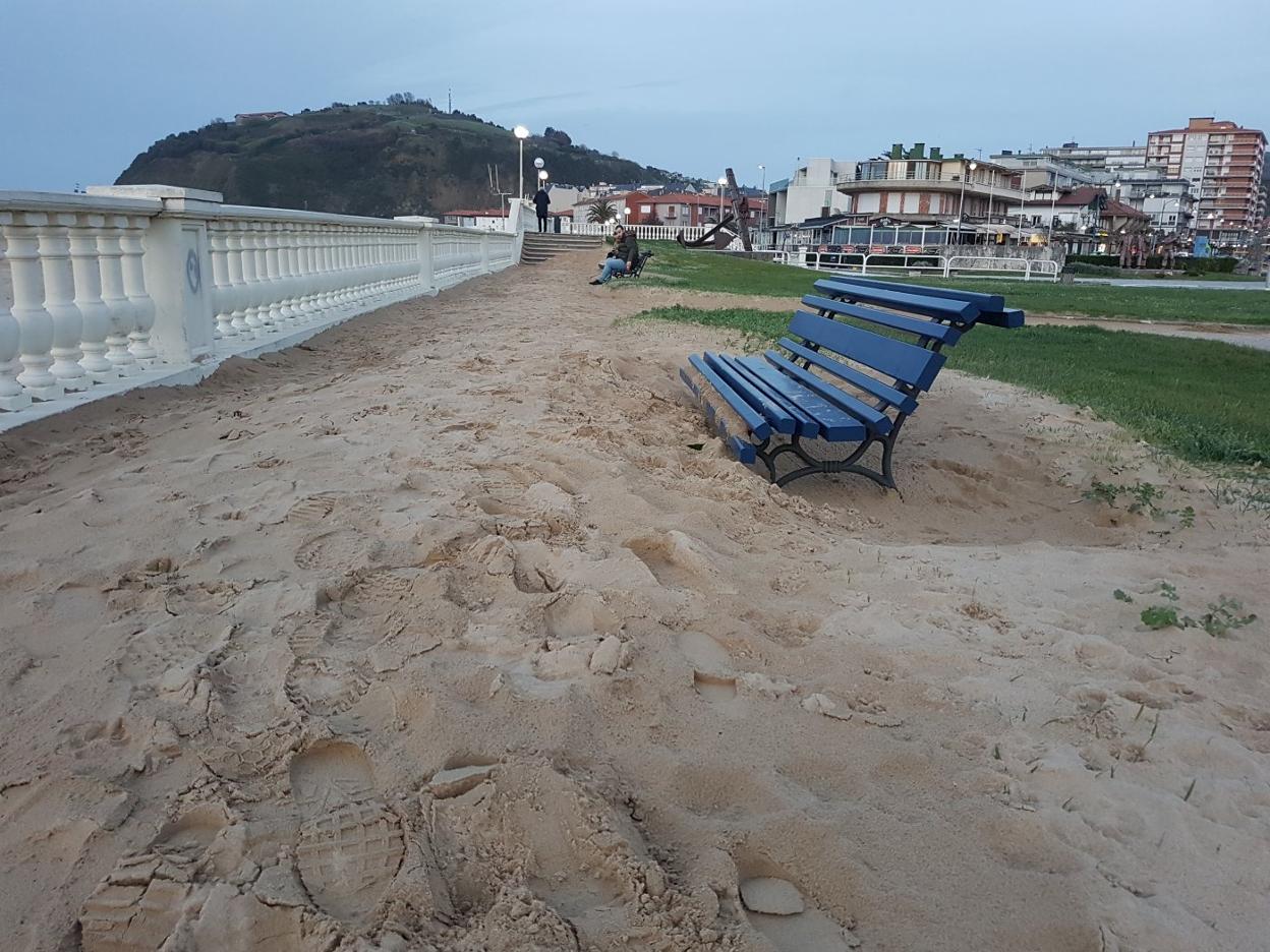 Un tramo del paseo marítimo invadido por la arena.