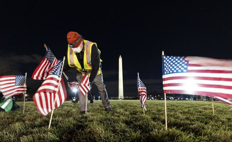 Un trabajador coloca las banderas que servirán de homenaje en la toma de posesión de Joe Biden.