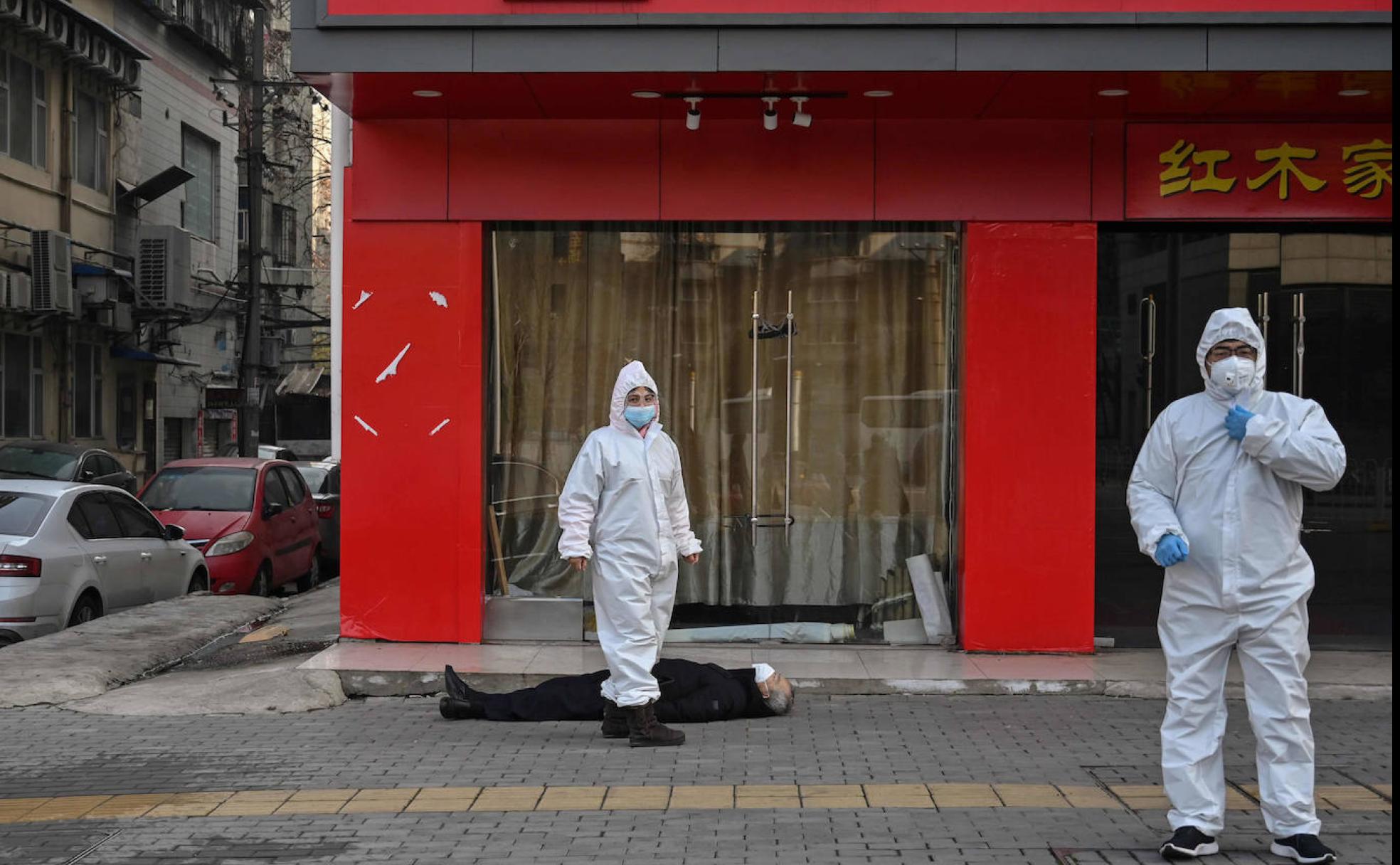 Técnicos sanitarios custodian en los accesos de un hospital de Wuhan el cadáver de una de las víctimas del coronavirus. 