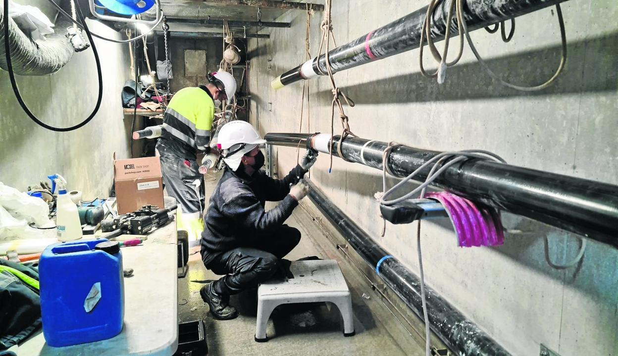 Dos operarios se disponen a empalmar el cable de alta tensión en un de los tramos de la línea, en Revilla de Camargo. .