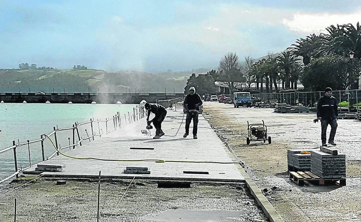 Los operarios trabaja en la colocación del nuevo pavimento de losetas de granito.