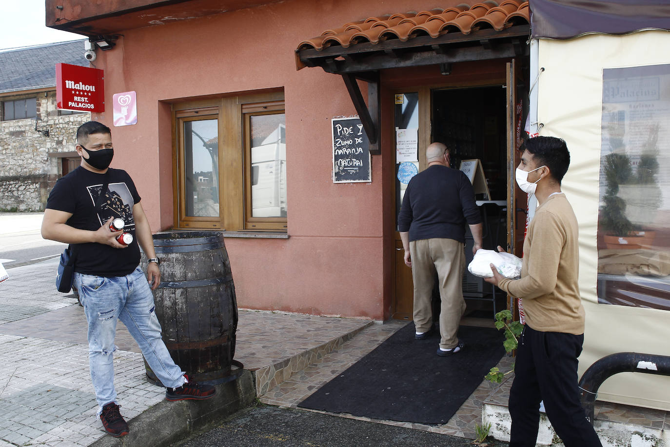 Imagen. Comida para llevar. en POlanco Darwin Morcillo y su compañero de reparto recogen un menú en el restaurante Palacios, en Requejada. El cierre les cogió por sorpresa. 