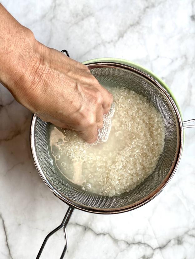 Lavar el arroz y escurrirlo en varias veces hasta que el agua salga limpio.