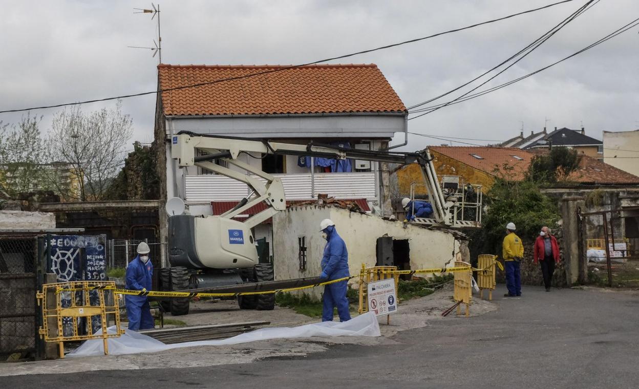 Los operarios retiran los restos de amianto de una de las edificaciones. 