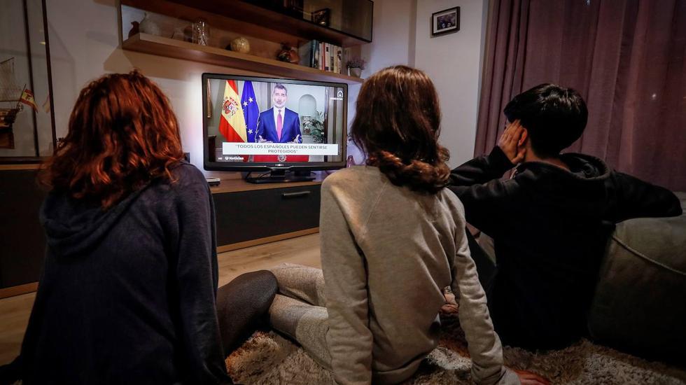 Miembros de una familia siguen el discurso extraordinario de Felipe VI del 18 de marzo. 