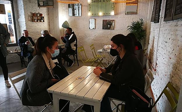 Imagen. Dos clienteas esperan a ser atendidas en el bar Santa & Co en el primer día con los interiores de los bares cántabros abiertos tras cuatro meses