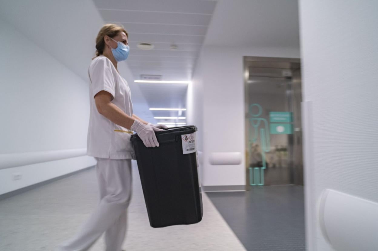 Una trabajadora transporta un contenedor de residuos en el Hospital Valdecilla.