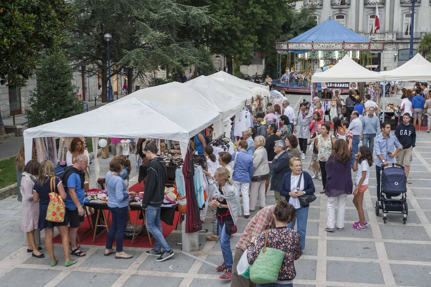 14/08/2014. Carpas de comerciantes en la Plaza de Pombo de Santander con el carrusel "Caballitos Penagos" al fondo