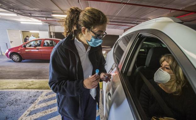 Mariluz Gijón, enfermera de la Unidad Epidemiológica, explica a Pilar cómo debe hacerse el test de saliva, ayer, en el 'coroauto' de Cazoña. 