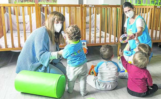 Verónica Pérez, directora de la Escuela Infantil Chiquitín, en Valdenoja, y una de las trabajadoras juegan con un grupo de niños en una de las salas de la guardería. 