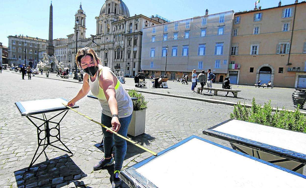 Una mujer prepara una terraza en la plaza Navona de Roma.