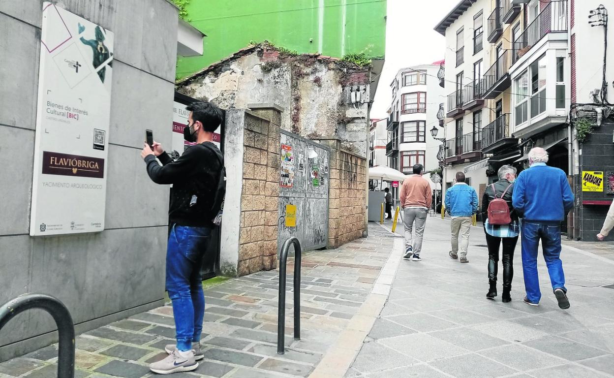 Un ciudadano escanea el código QR en el yacimiento romano de Flavióbriga. 