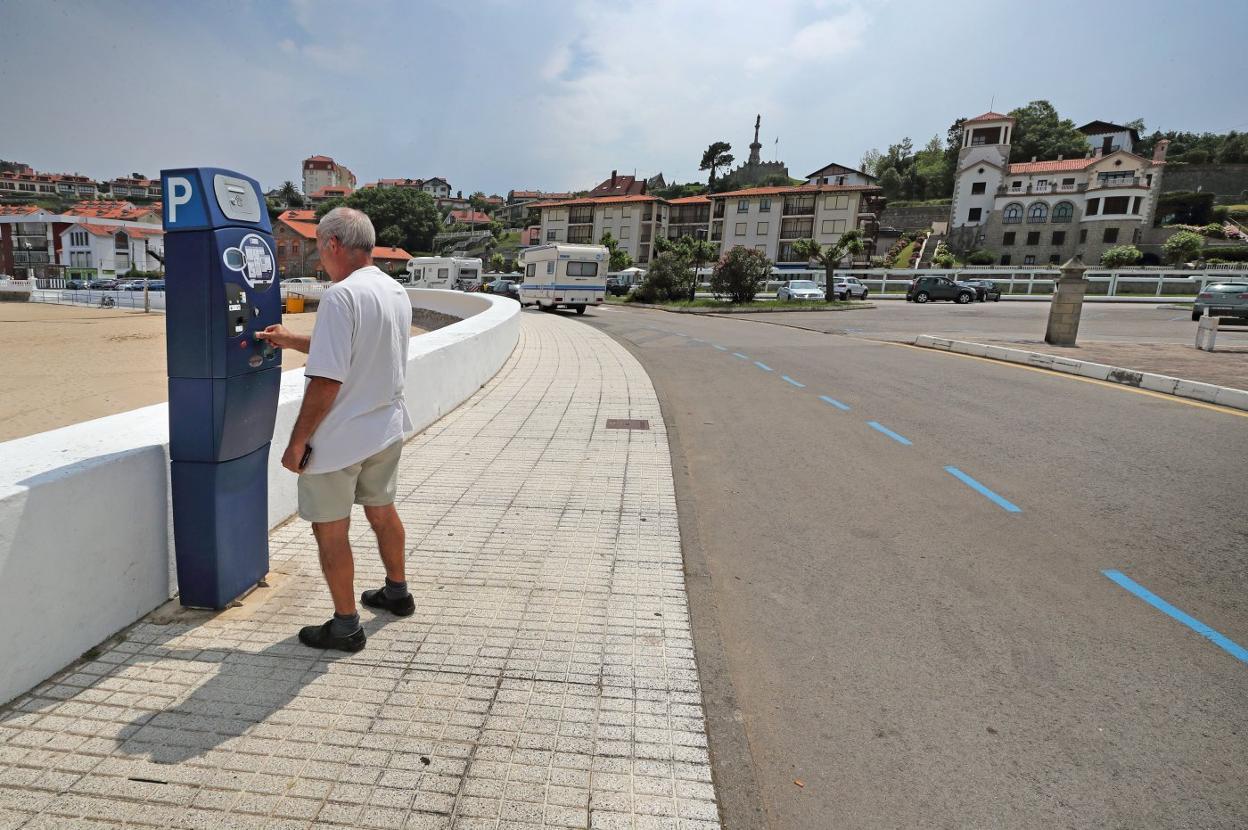 Un hombre saca un tique de aparcamiento en la zona azul de la playa de Comillas. 