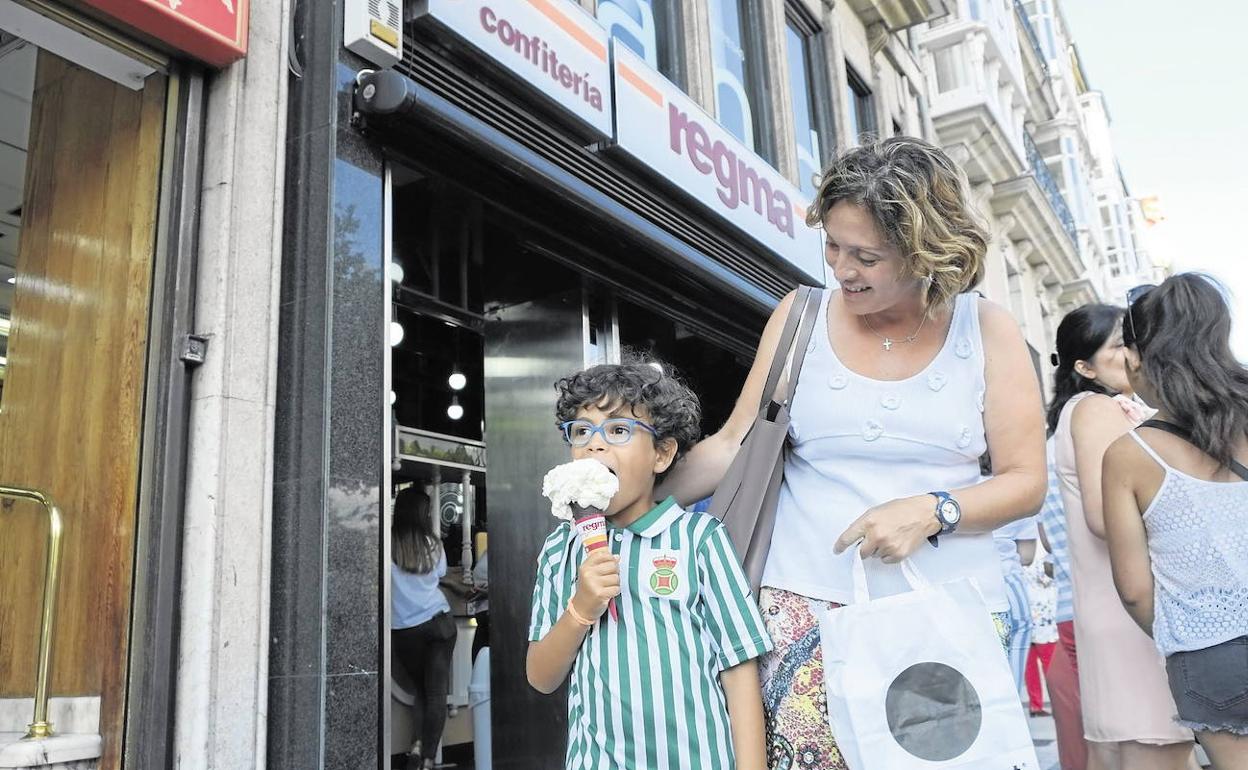 Un niño saborea un helado junto a su madre a la salida de una de las heladerías en Santander.