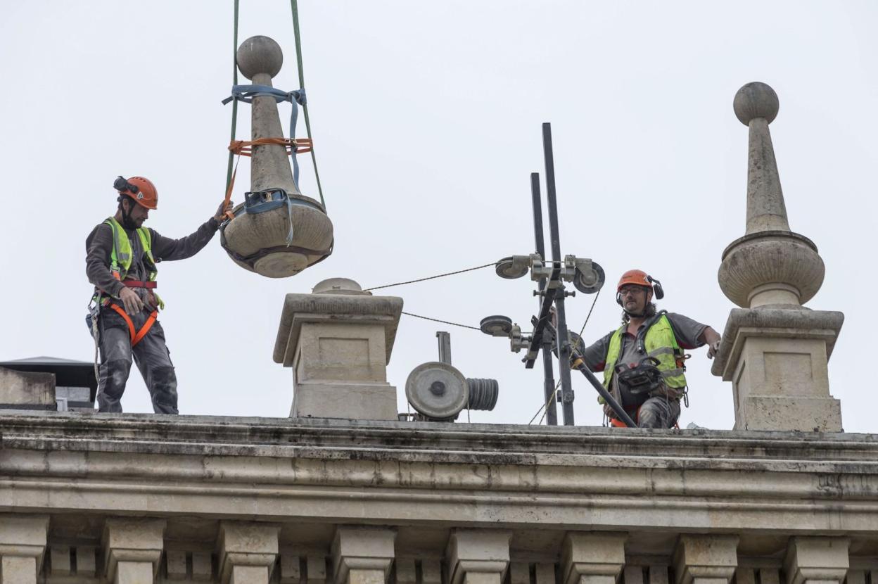 Los operarios retiran los pináculos que presiden el edificio del Banco Santander desde la parte superior. 
