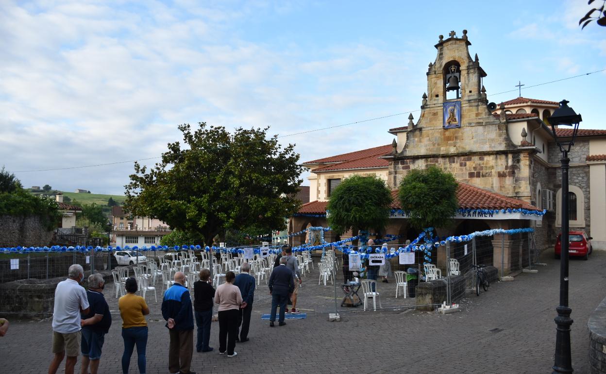 Vecinos de Revilla y de todas partes de Cantabria forman una hilera frente a la parroquia de Revilla de Camargo, en el día del Carmen de 2020, durante las visitas a la patrona controladas con medidas de seguridad. 