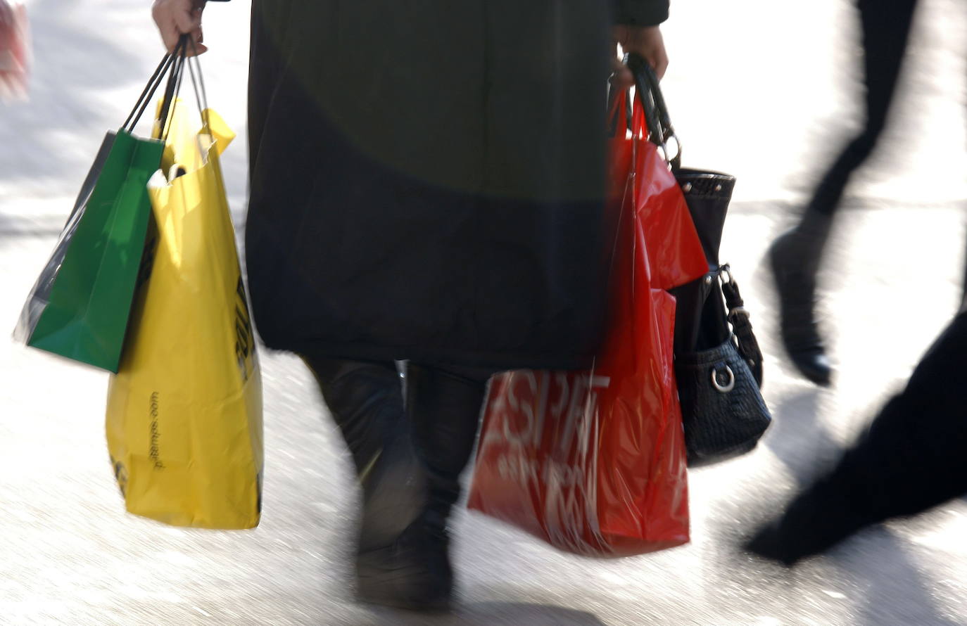 Una señora pasea con bolsas de la compra. 