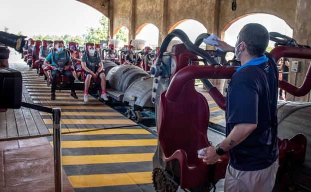 Un trabajador de PortAventura da instrucciones a los visitantes en una montaña rusa tras la reapertura del parque. 