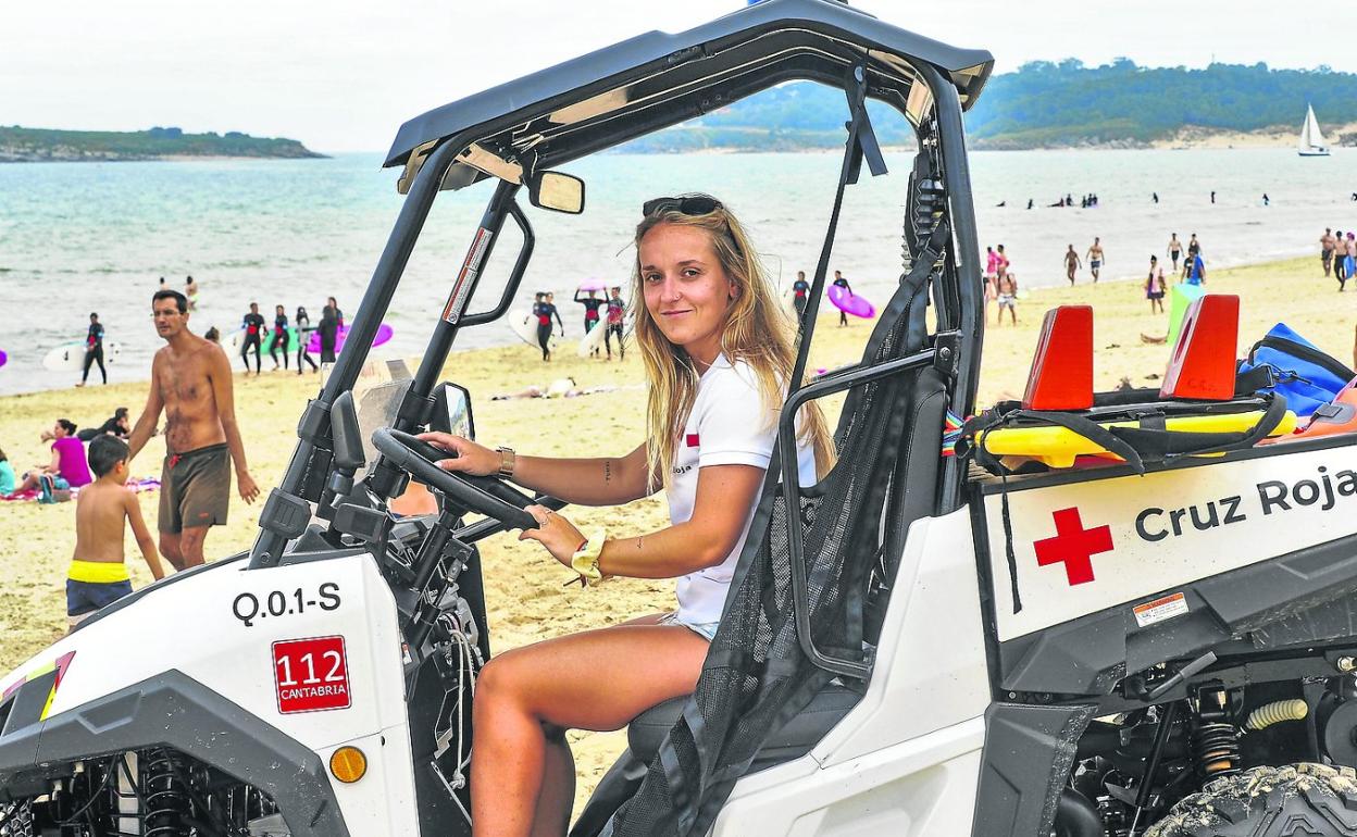 Andrea Martos posa sentada en un quad de Cruz Roja en la playa de Somo, con los bañistas y el mar de fondo. 