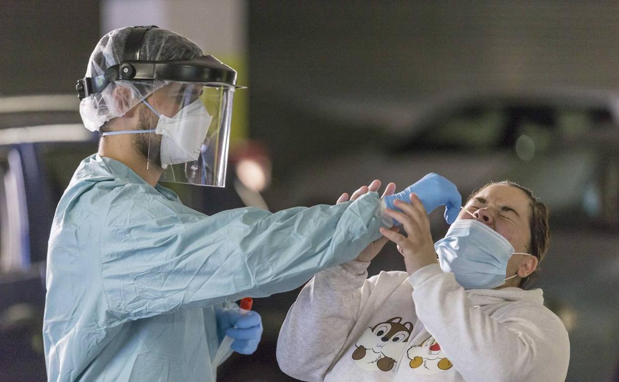 Un sanitario de la Unidad de Vigilancia Epidemiológica e Intervención recoge una muestra en el coroauto del aparcamiento de Cazoña, en Santander.