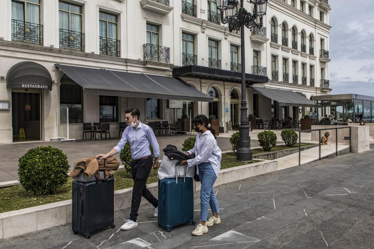 Dos turistas, con sus maletas, junto al Hotel Sardinero de Santander. 