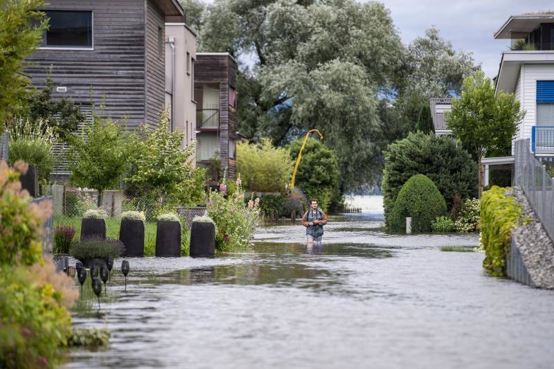 Un hombre camina con el agua a la altura de las rodillas en el vecindario de Ried, cercano al lago Sarnen, Suiza.