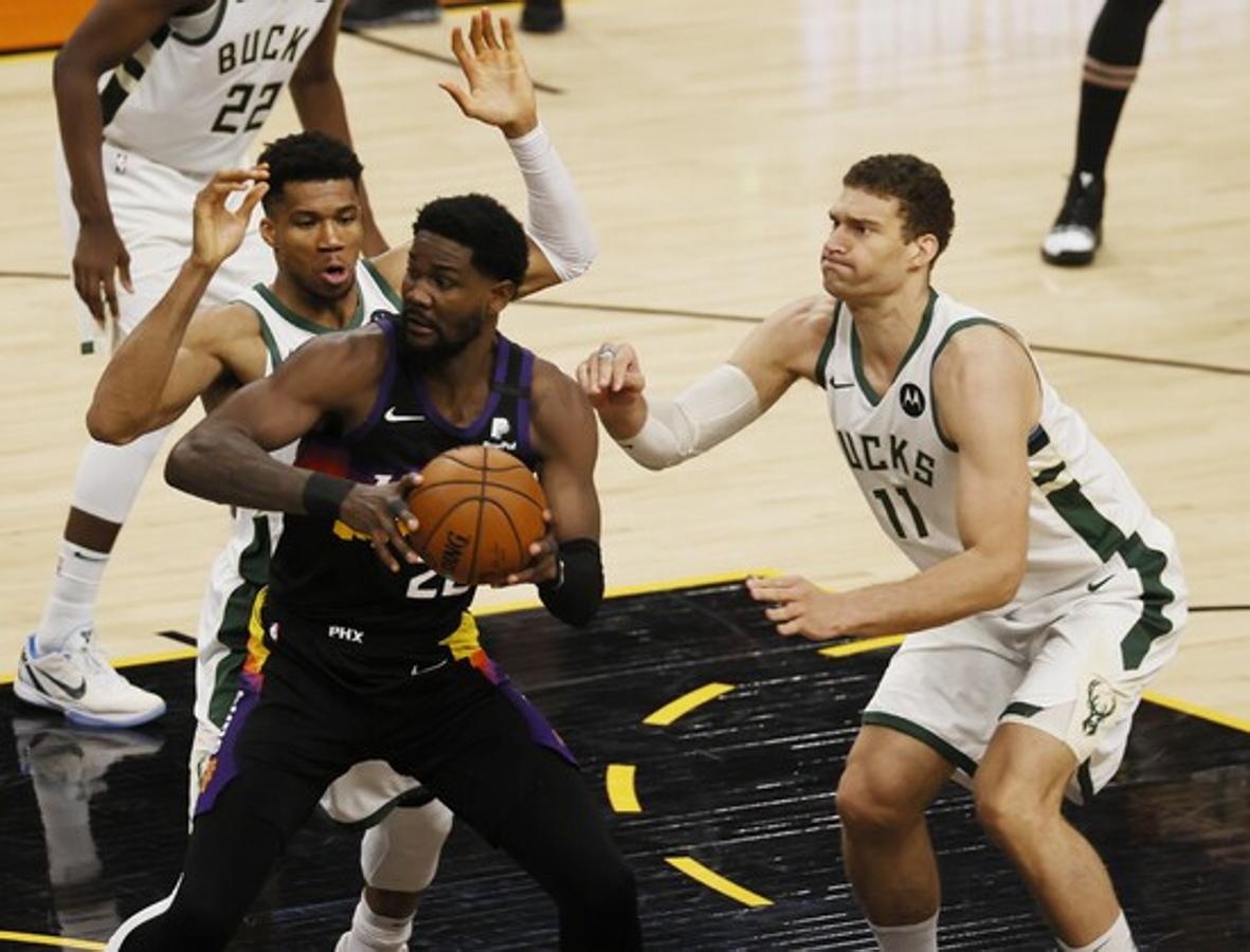 Deandre Ayton, jugador de los Phoenix Suns, franqueado por Giannis Antetokounmpo y Brook Lopez durante el tercer cuarto del partido.