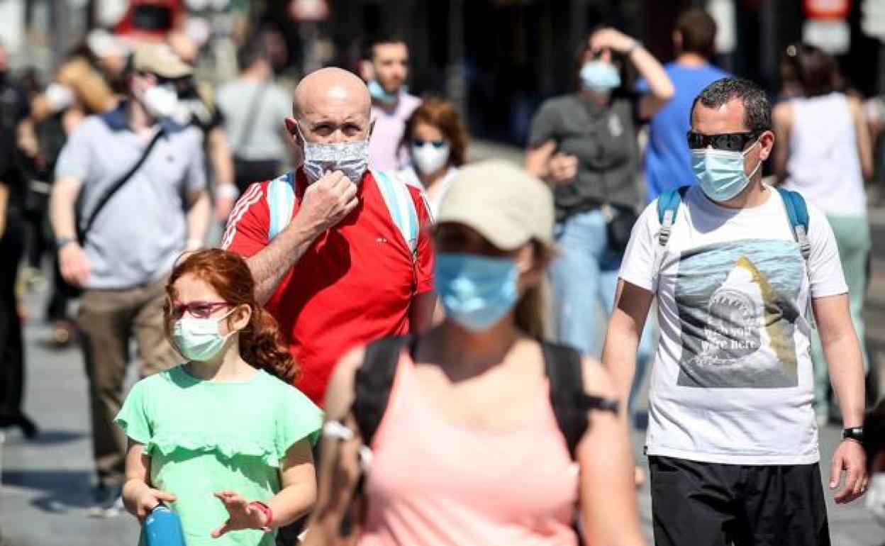 Varias personas pasean con mascarilla. 