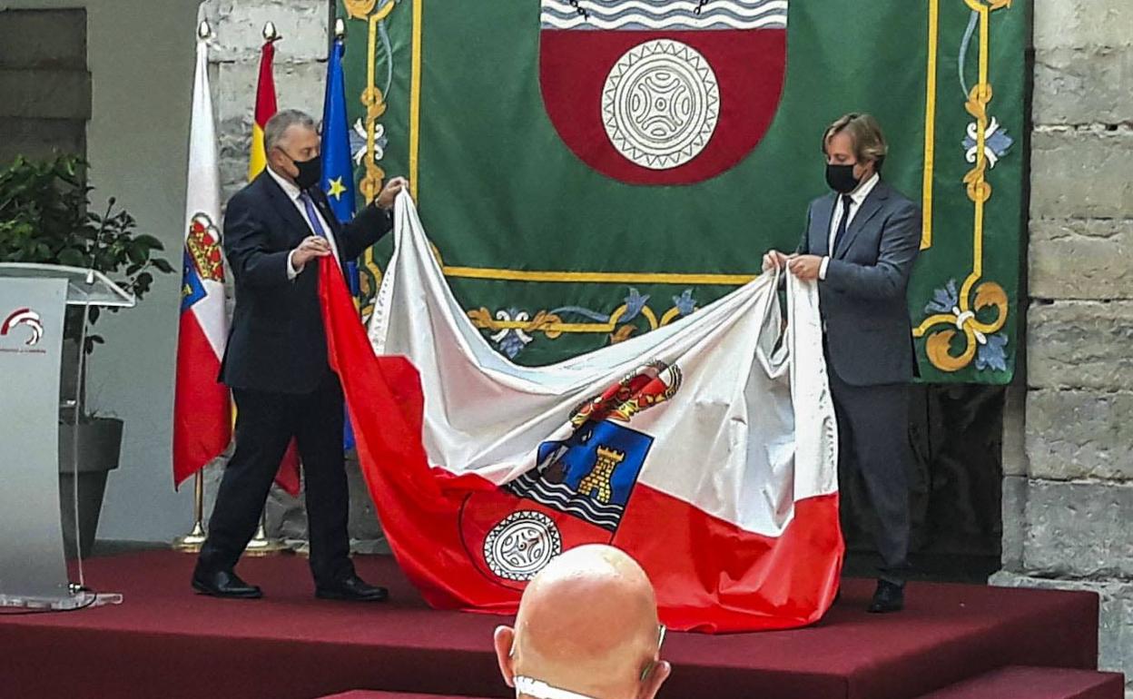 Joaquín Gómez en el momento de entregar la enseña de Cantabria al alcalde de Reocín, Pablo Diestro