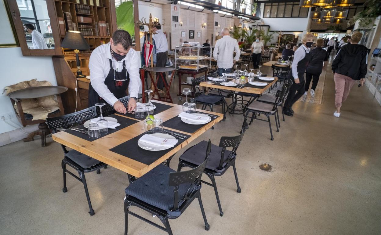 Un camarero prepara una de las mesas en el interior de La Taberna del Herrero, en Santander. 