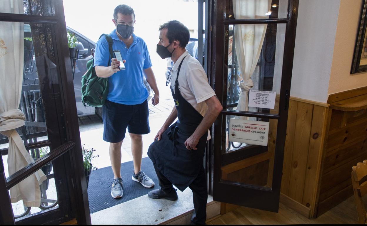 Un camarero solicita a un cliente que enseñe el pasaporte covid para acceder a un local de hostelería.