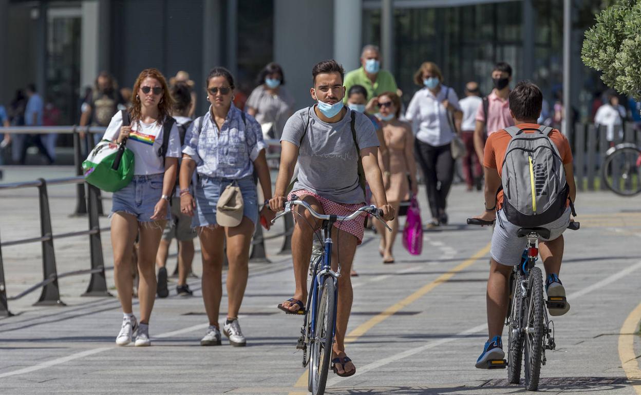 Dos jóvenes se desplazan en bicicleta en el céntrico carril del paseo marítimo de Santander.