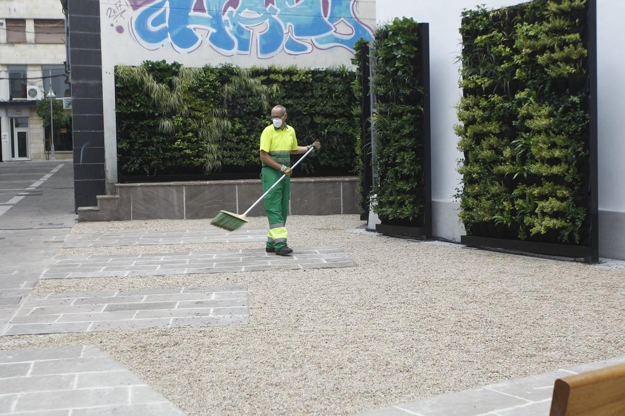 Un trabajador municipal realiza labores de limpieza en el microespacio cultural en el que se levanta el jardín vertical.