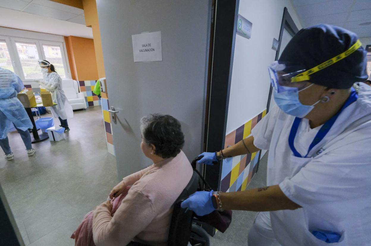 Una profesional de la residencia San Miguel, en Meruelo, acompaña a una residente a pincharse en la jornada de vacunación del centro.