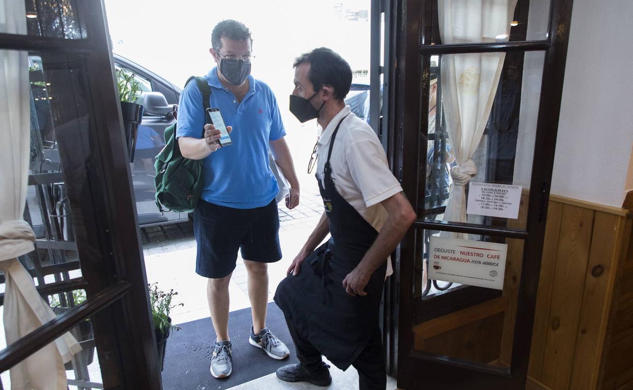 El cliente de un local de hostelería muestra su certificado en la puerta.