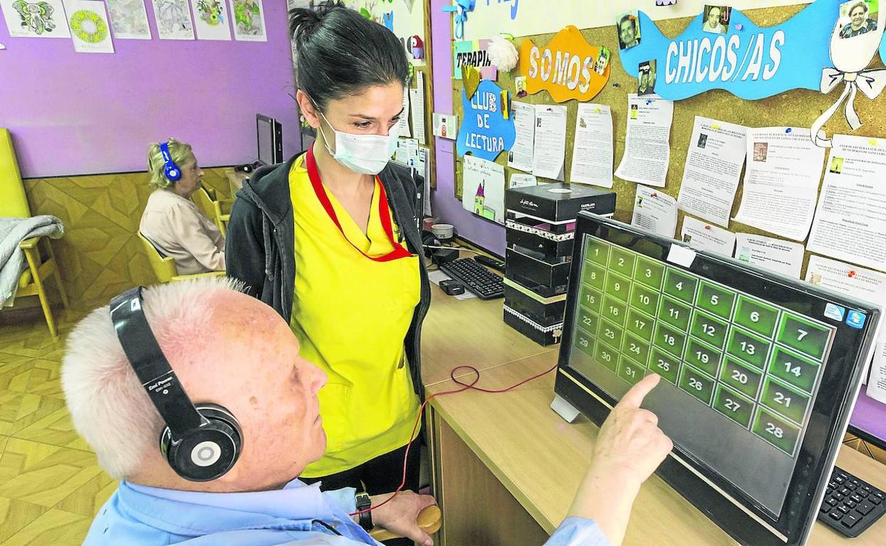 Una profesional acompaña a un residente en una de las actividades programadas para mejorar la agilidad mental. 