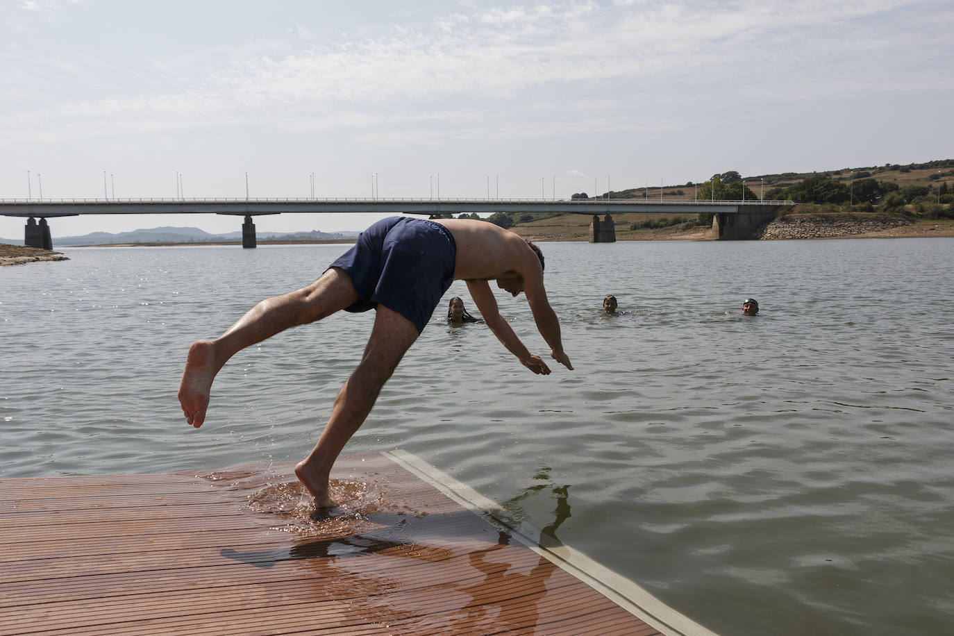 Un hombre disfruta del pantano del Ebro saltándo al agua de cabeza