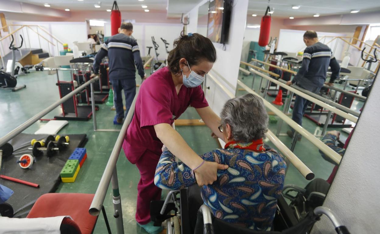 Una trabajadora de Padre Menni ayuda a una paciente en su trabajo de rehabilitación. 