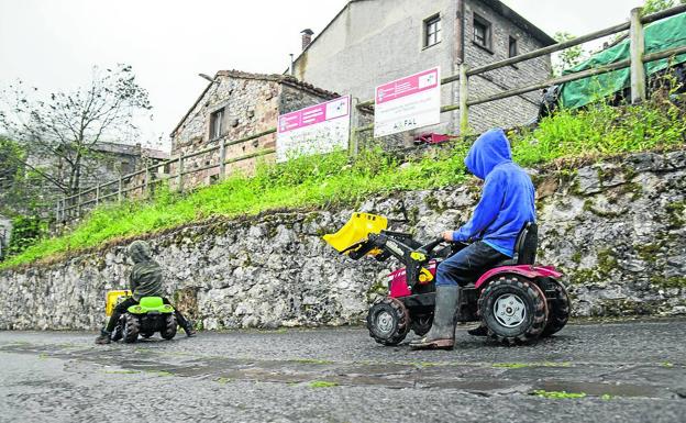 Dos niños se divierten lanzándose cuesta abajo con sus tractores de juguete. 