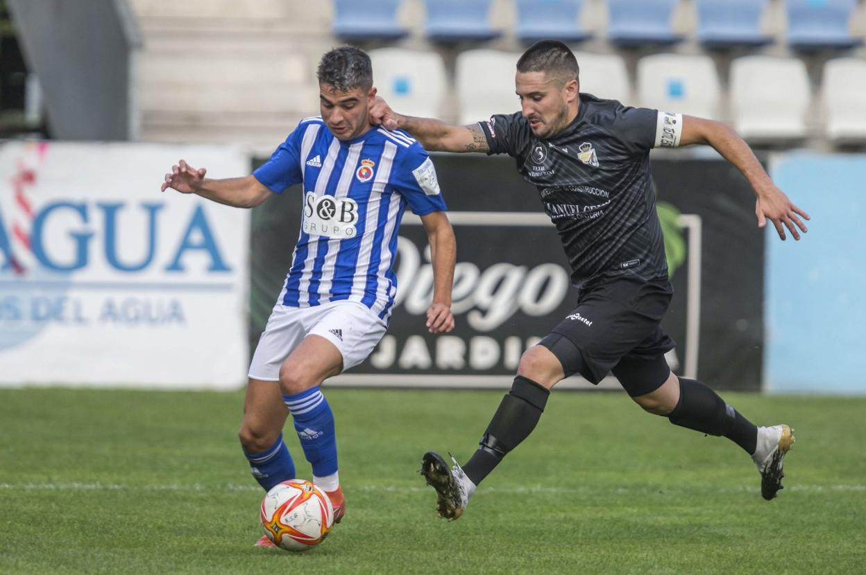 Tirado, de la Gimnástica, controla el balón ante San Emeterio, del Escudo. 