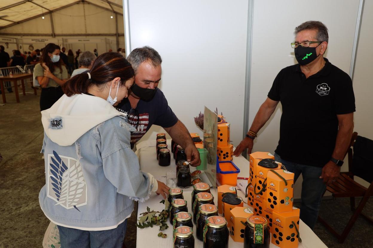 Una pareja hace una degustación en uno de los expositores de miel en Vega de Liébana. 