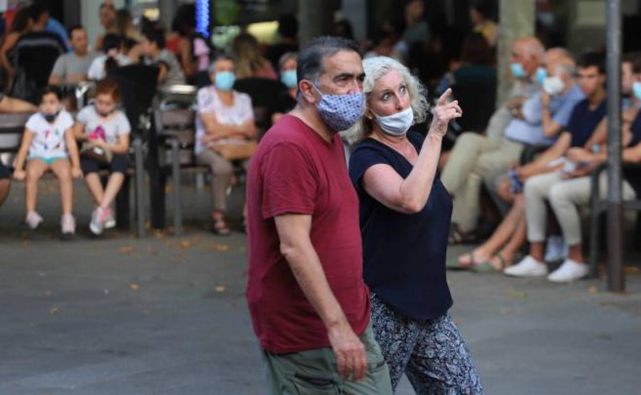 Una pareja pasea con la mascarilla puesta. 