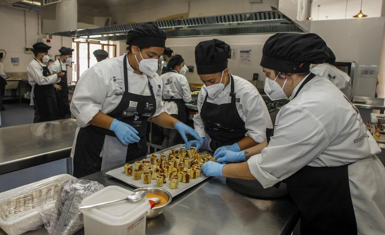 Alumnos participantes en uno de los cursos de hostelería de la Escuela Taller de Barreda preparan un plato. 