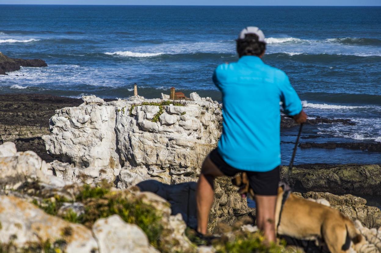 Un caminante por la senda costera señalaba ayer las dos esculturas en lo alto de la roca junto a su perro