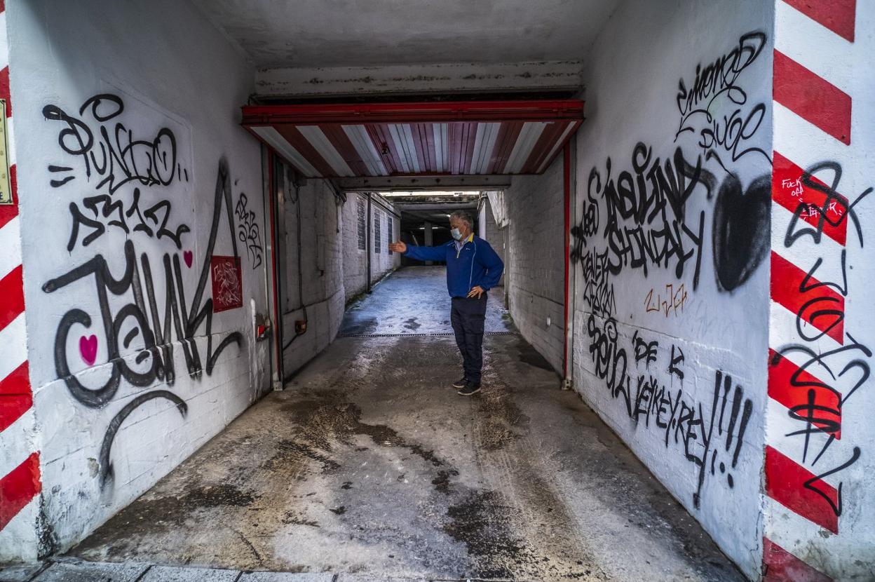 Un responsable de mantenimiento muestra las pintadas existentes en los accesos a un garaje de la calle Santa Lucía. 