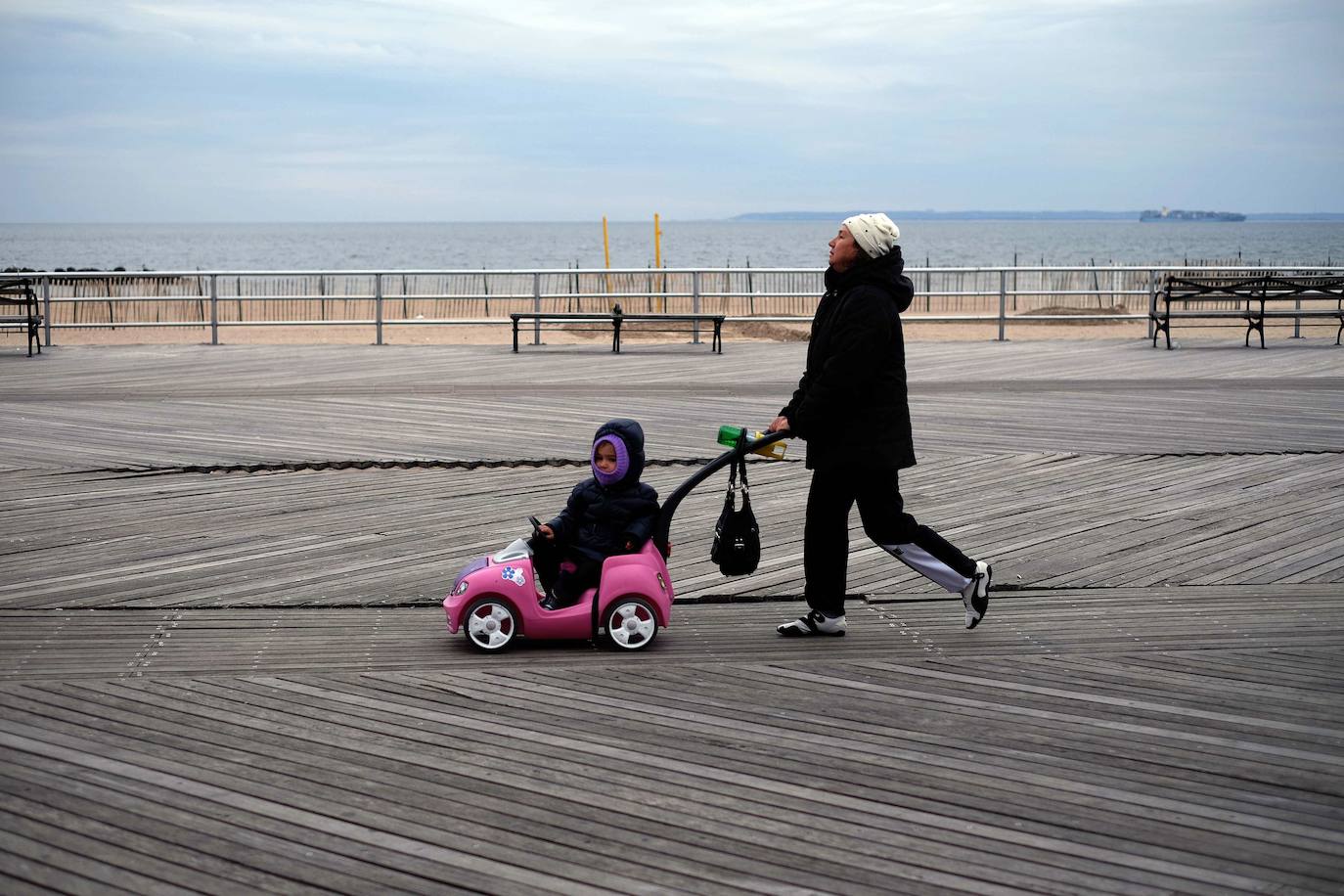 Una mujer camina con un niño por el paseo marítimo de la playa de Coney Island en el distrito de Brooklyn de Nueva York. Esta ciudad se está preparando para el aumento del nivel del mar que traerá el cambio climátio.