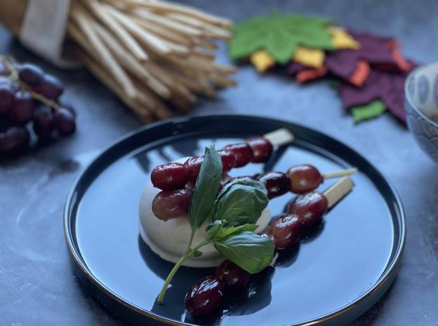 Emplatar la burrata y colocar encima las brochetas de uvas.