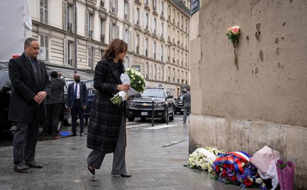 Kamala Harris se dispone a depositar un ramo de flores.