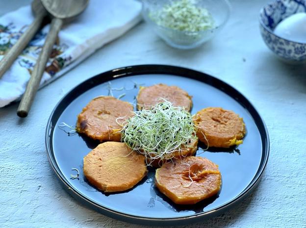 Empieza a emplatar colocando las rodajas de calabaza y, en el centro del plato, un montoncito de germinados de cebolla.